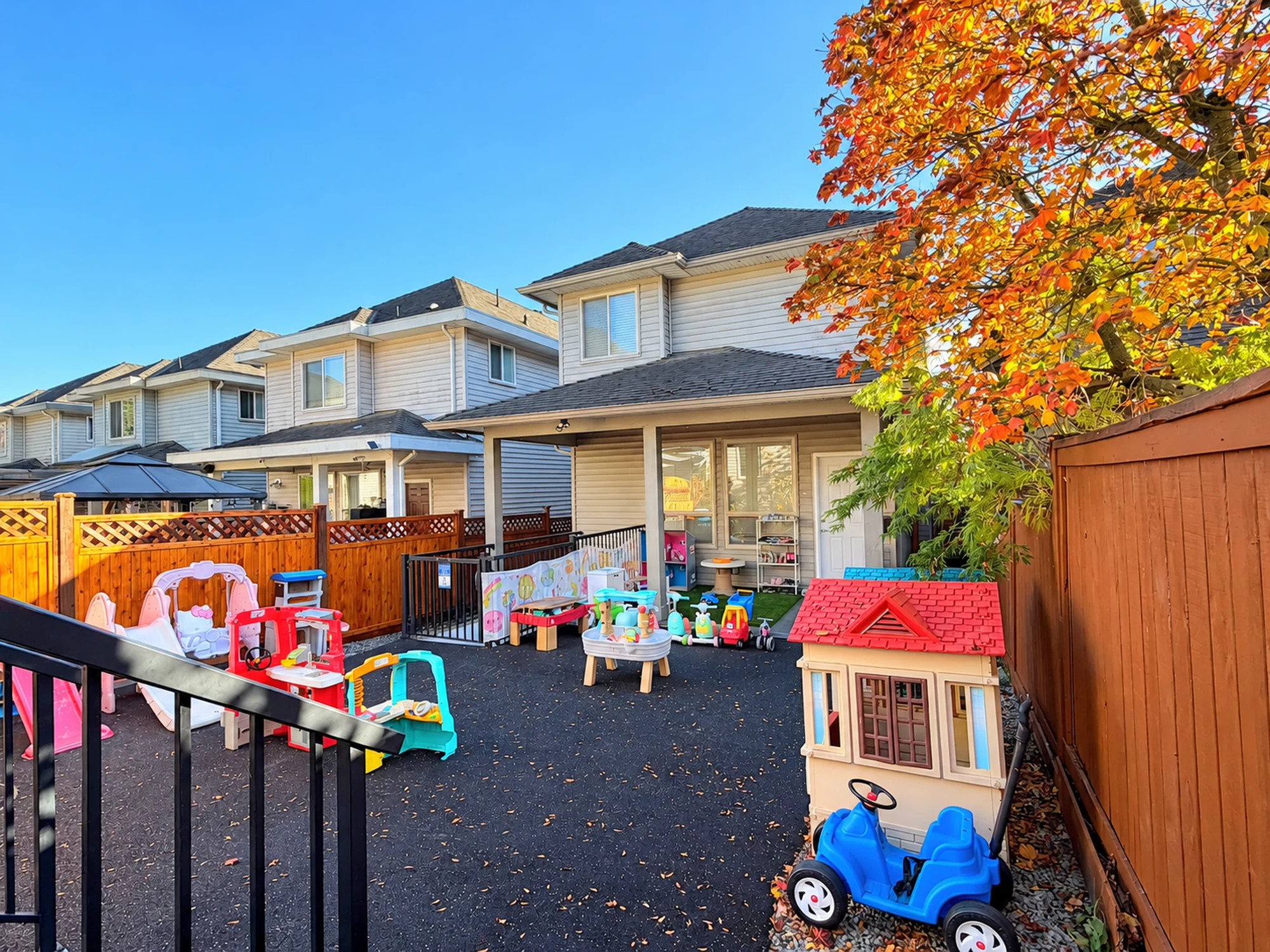 Outdoor playhouses and activity stations beside the autumn tree