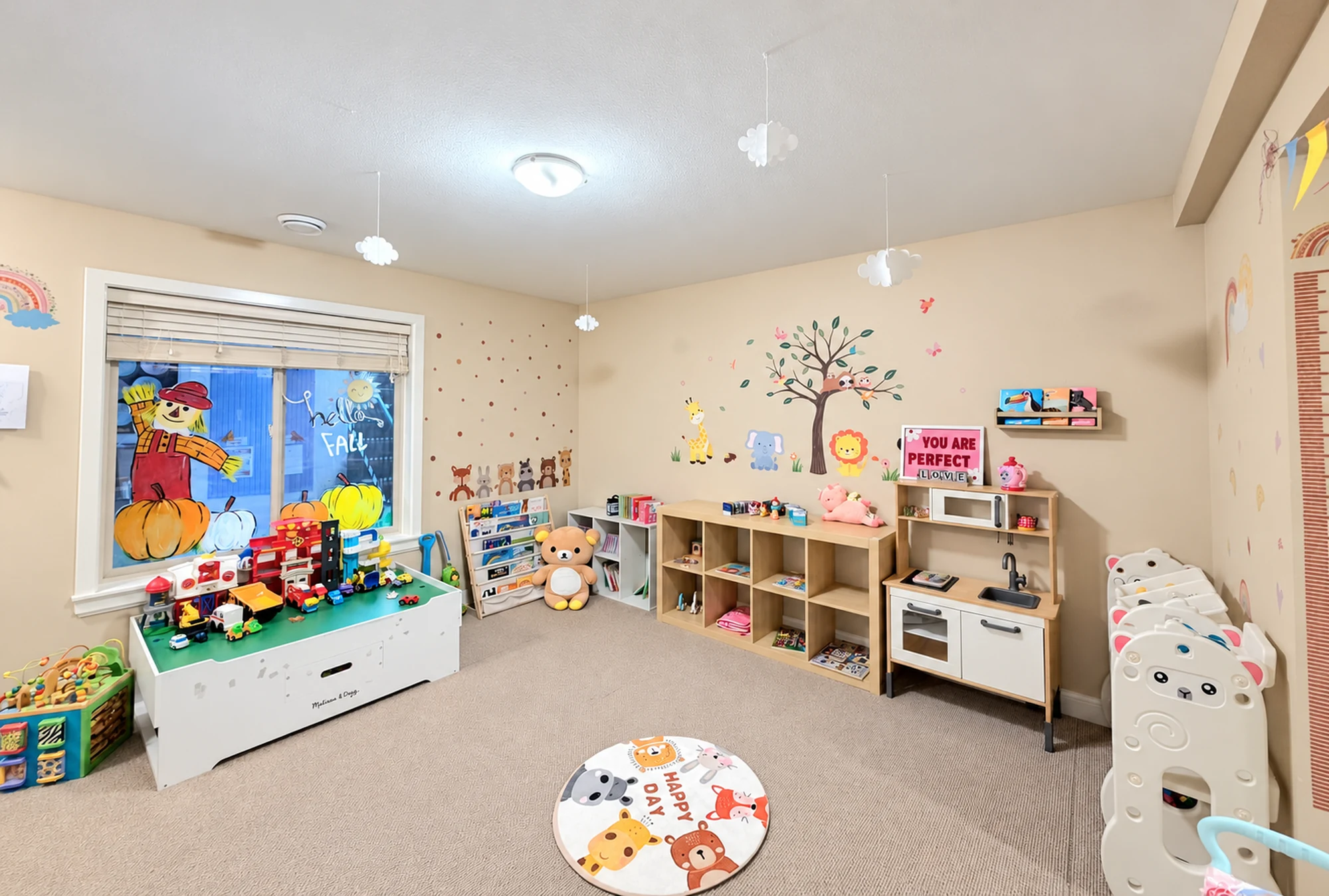 A bright playroom corner with a toy kitchen, books, shelves, and cloud decorations.